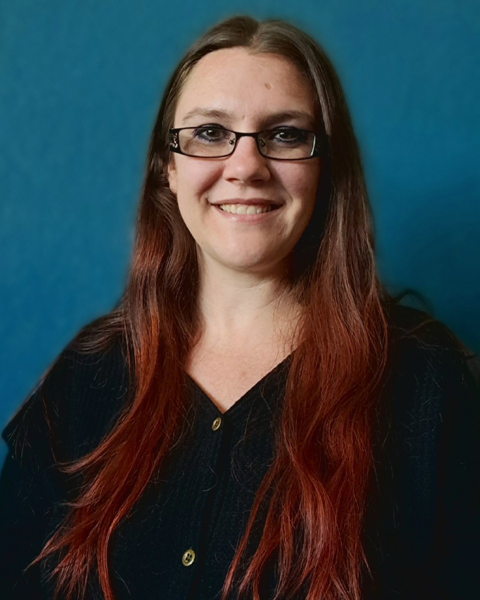 Portrait of Stephanie Batty, LMFT, smiling, with long auburn hair and glasses